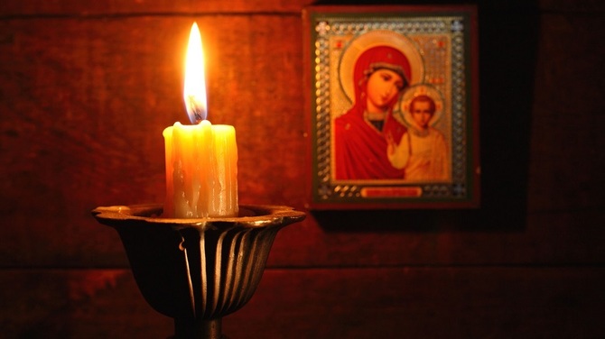 23256260 - closeup of lighting candle on wooden background with christian icon